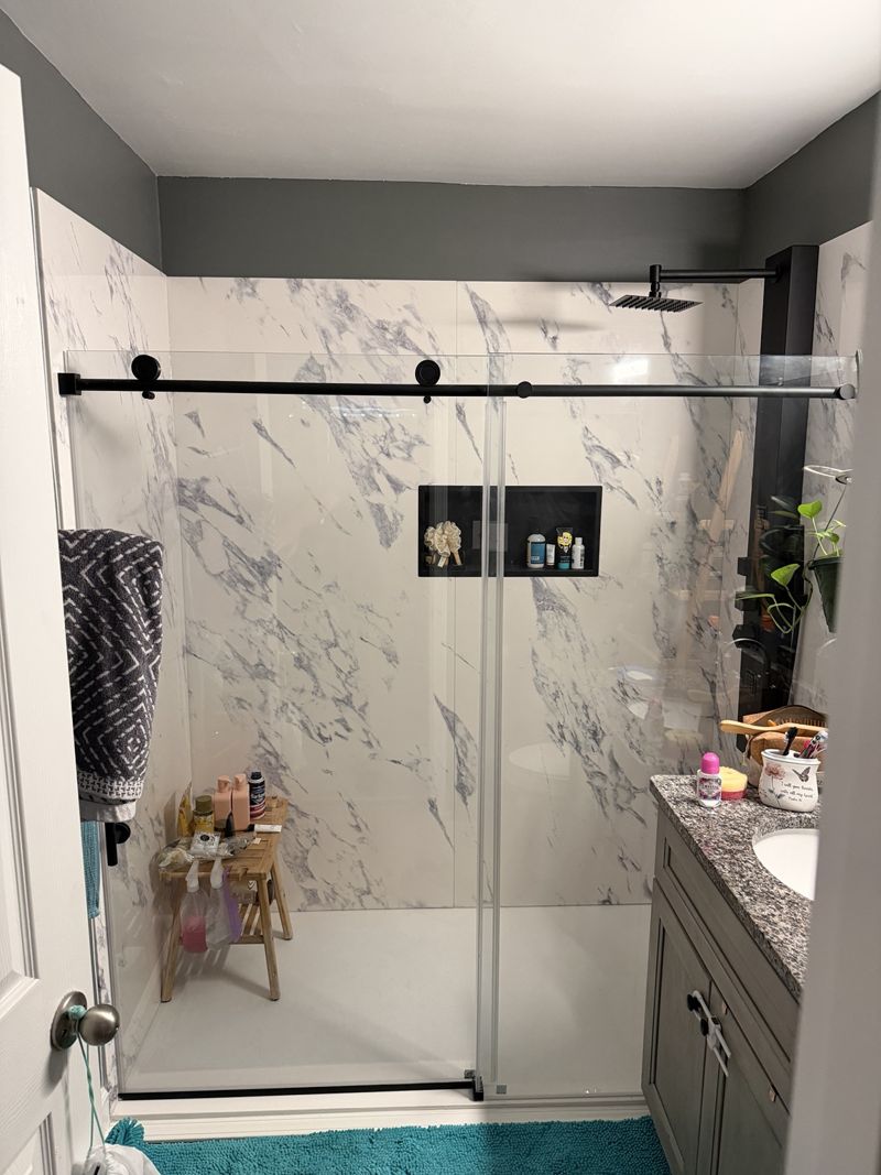 Bathroom with marble-look shower surround and glass shower door