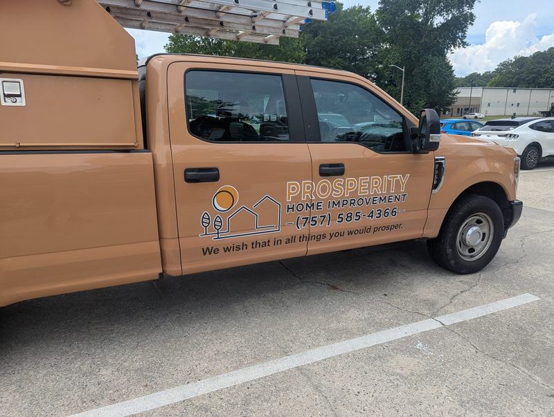 Tan pickup truck with Prosperity Home Improvement logo, phone number and ladder rack