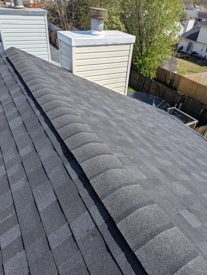 Dark gray shingle roof ridge with two white-sided chimney chases