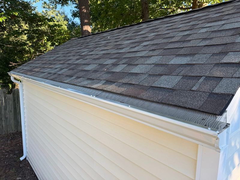 Pale yellow vinyl siding under a gray architectural shingle roof with white gutter