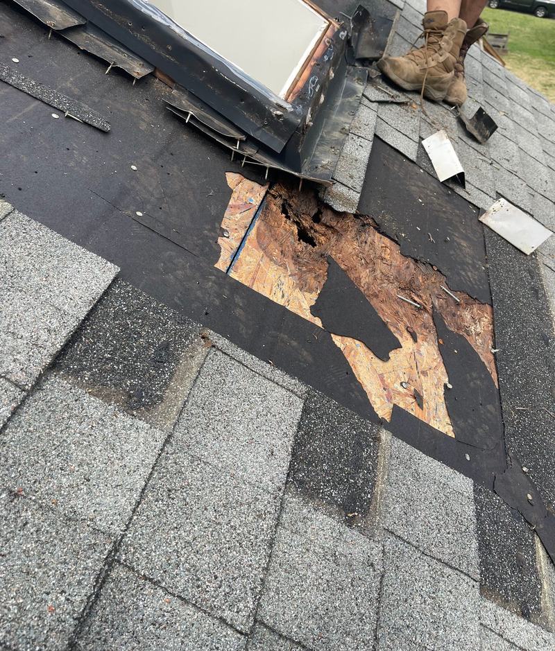 Roof section opened beside a skylight showing water-damaged, rotted wood decking